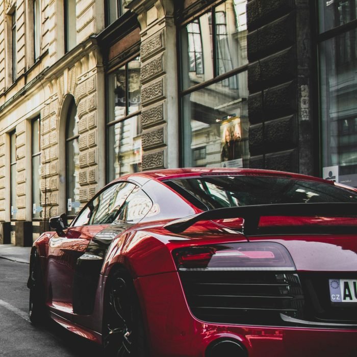 Sleek red sports car parked on a charming historic street in Prague, highlighting urban elegance and powerful design.